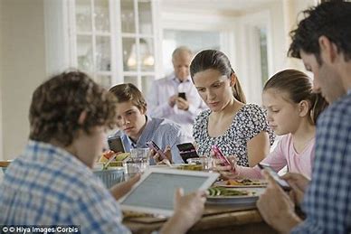 a family around a table looking at their phones