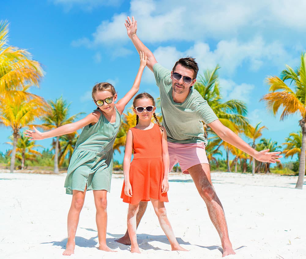 a dad and his daughters posing at the beach